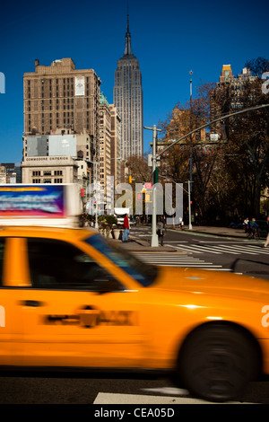 Traditional NYC Yellow taxi, Empire State building in the background, USA Stock Photo