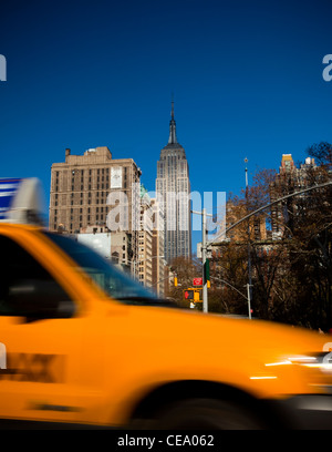 Traditional NYC Yellow taxi, Empire State building in the background, USA Stock Photo