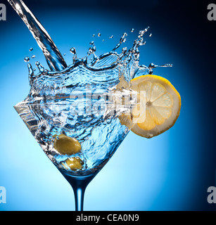 Splash from pouring martini into the glass. Object on a blue background. Stock Photo