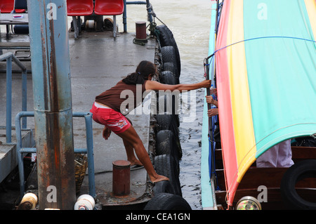 Thai girl pulls long tail boat to pier, Chao Phraya river, bangkok, Thailand Stock Photo