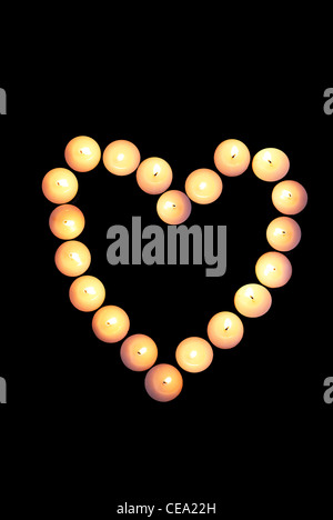 Heart shape made from tealight or nightlight candles on black background Stock Photo