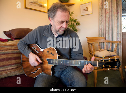 A middle aged man playing a Taylor acoustic guitar, UK Stock Photo