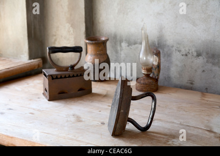 The old iron, oil lamp and jug on a wooden table Stock Photo