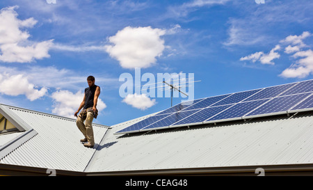 Workman installing Solar Power Panels on domestic roof Stock Photo