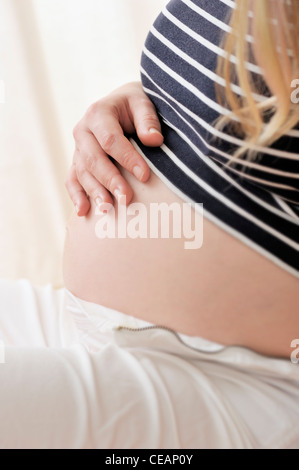 Pregnant woman holding a hand on her belly Stock Photo