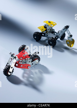 shot of two small metal mechano toy vehicles on a beige backdrop Stock Photo