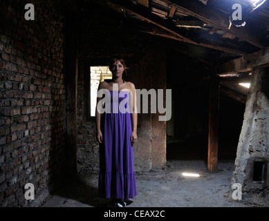 Lonely young woman standing in attic Stock Photo