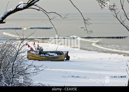 Fishing boat on the snow-covered beach in Rewal, on the west coast of the Baltic Sea in Poland. Winter on the Baltic Sea Stock Photo