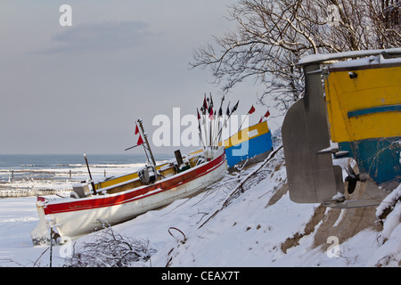 Fishing boats on a snow-covered beach in Rewal, Poland. Winter by the sea. Stock Photo