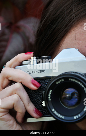 A young girl with an old vintage camera taking a picture Stock Photo