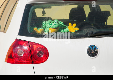 Frog flurry puppet left inside a white car parked in the sun Stock Photo