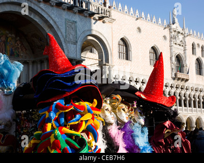Venice, Veneto, Italy. Colourful souvenir stall selling carnival kitsch, the Palazzo Ducale beyond, Piazza San Marco. Stock Photo