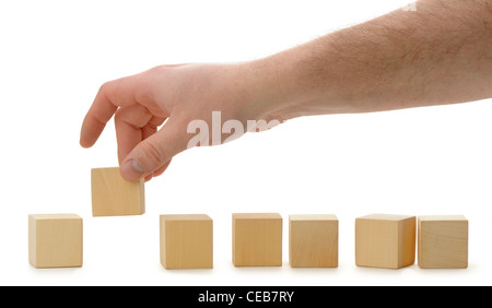 The hand establishes a wooden cube in row. It is isolated on a white background Stock Photo