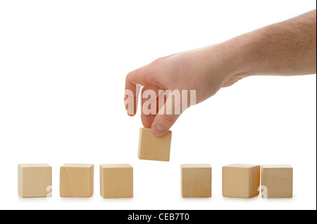 The hand establishes a wooden cube in row. It is isolated on a white background Stock Photo