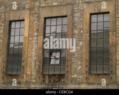 A CCTV camera on the side of a factory made with stone walls and industrial windows Stock Photo