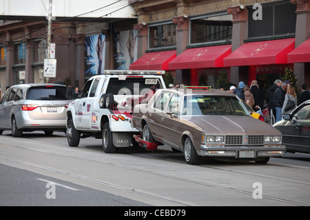 Tow truck hauling a car on street in downtown Toronto Canada Stock