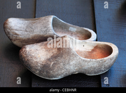 Old used traditional dutch wooden clogs on a wooden surface. Stock Photo