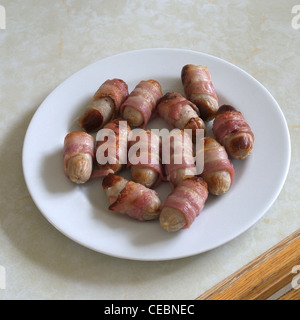 A Selection of Pigs In Blankets (sausages wrapped in bacon) on a White Plate