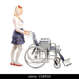 Full length portrait of a young girl pushing a wheelchair isolated on white background Stock Photo