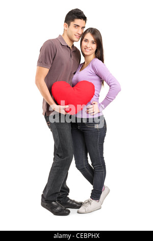 Full length portrait of a young loving couple holding a red heart shaped pillow isolated on white background Stock Photo