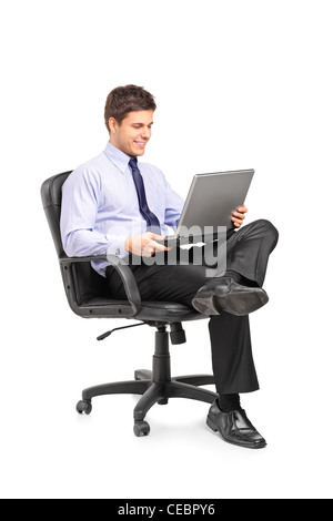 Young smiling businessman sitting in office chair and working on laptop computer isolated on white background Stock Photo