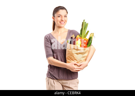 A smiling female holding a paper bag full of groceries isolated on white background Stock Photo