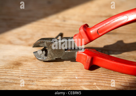 Nippers with the clamped nail on a wooden table Stock Photo