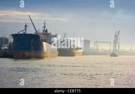 Two tankers in the harbor at sunrise on a blue and golden misty morning Stock Photo