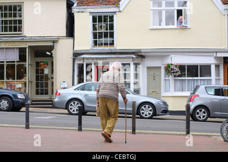 Elderly man walking with stick in Market Hill, Woodbridge, Suffolk, UK Stock Photo