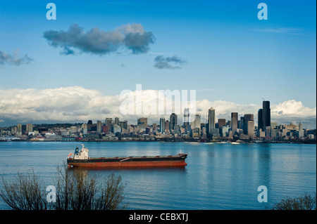 A large ship waits anchored in Elliott Bay in front of the Seattle, Washington waterfront for a tug during a beautiful sunset. Stock Photo
