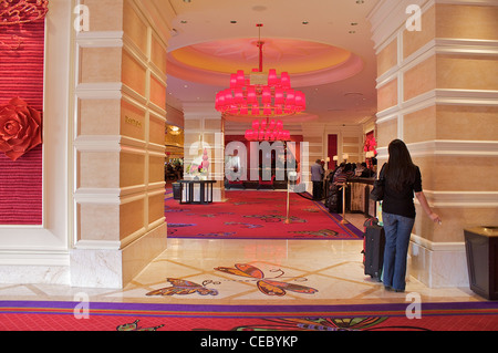 A woman stands with a suitcase near the reception area at the Wynn Encore hotel and casino in Las Vegas Stock Photo