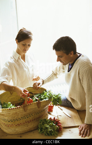 Couple removing fresh produce from basket Stock Photo