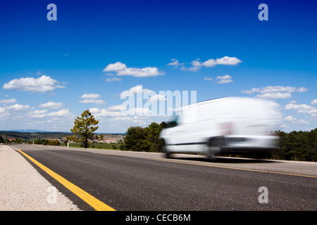 White van in a country road with some trees and a great blue sky above Stock Photo