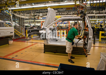 A factory worker installs door hardware on an F-150 pickup truck at the Ford final assembly plant production line Stock Photo