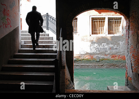 Man crossing bridge over a canal in the back-streets of  Venice, Italy Stock Photo