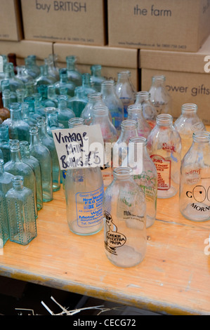 Assorted collectable empty vintage aqua & clear glass milk bottles displayed (£5 on price label) - antique fair, Harrogate, Yorkshire, England, UK. Stock Photo