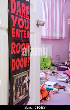 Bedroom door poster (Dare you enter the room of doom?) & child's (girl's) cluttered messy room, toys scattered lying on floor - Yorkshire, England, UK Stock Photo
