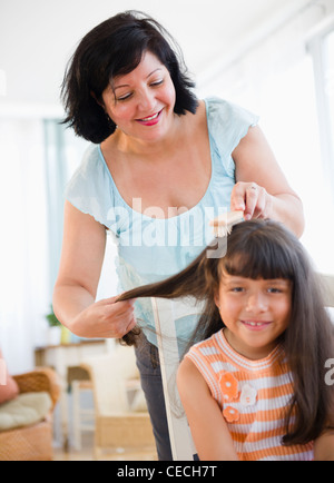 Hispanic woman brushing daughter's hair Stock Photo