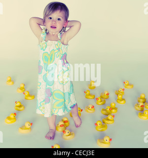 Caucasian girl standing with lots of rubber ducks Stock Photo
