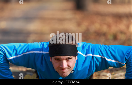 Portrait of a young man doing push-up outdoors in a park in autumn. Stock Photo