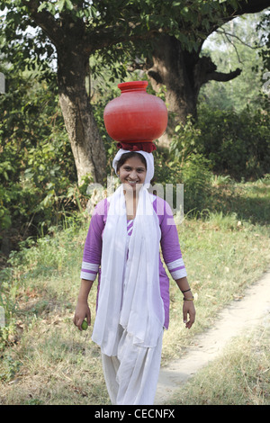 Indian woman  carrying water pots to fill from well ,Villagers have to fetch water from its natural sources. India Stock Photo