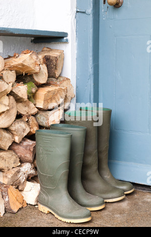 Green wellington boots alongside firewood in a porchway Stock Photo - Alamy