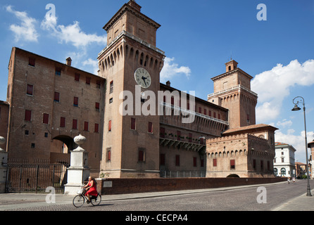 A Female Cyclist passes the Castello Estense Ferrara Emilia-Romagna Italy Stock Photo