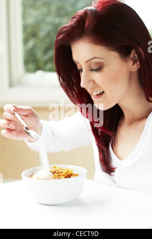 Girl pouring sugar on cereal Stock Photo