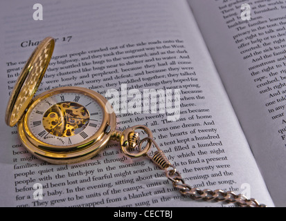 gold skeleton half face pocket watch on pages of a book Stock Photo