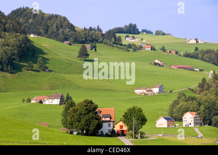 Horizontal view of typical Swiss countryside dotted with small farmhouses and homes amongst the rolling green hills. Stock Photo