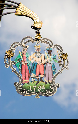 Vertical close up of an old ornately decorated wrought iron sign hanging on a building in Appenzell in Switzerland Stock Photo