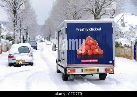 A tesco supermarket shopping groceries delivery van vehicle delivering food in the snow snowy winter wintry weather UK Stock Photo