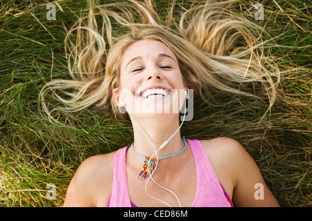 Caucasian woman laying in grass listening to music