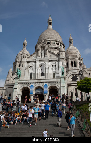 Tourists walking up and sitting on the steps leading to Basilique du Sacre Coeur in Montmartre Paris France Stock Photo